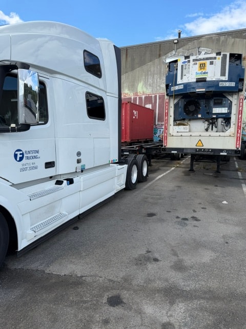 Flintstone Trucking semi-truck beside a refrigerated trailer