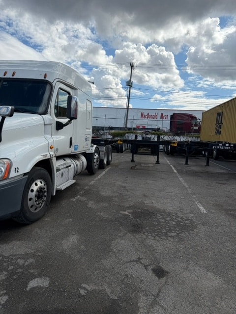 Flintstone Trucking white semi-truck with chassis in a freight yard